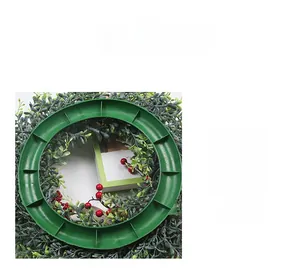 Détail de la base robuste en plastique vert et du feuillage dense de la couronne festive