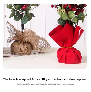 Dettaglio di bonsai di agrifoglio con basi in iuta e tessuto rosso per decoro festivo