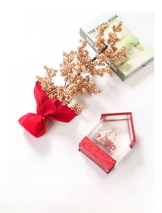 Close-up of golden faux berries and festive red house figurine for holiday decoration