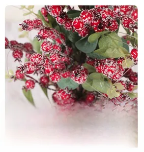 Dettaglio di rami di agrifoglio artificiale con bacche rosse e neve finta decorativa