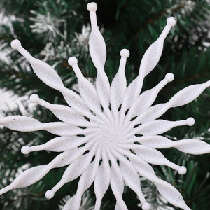 White glitter snowflake ornament hanging on a green Christmas tree for holiday decoration