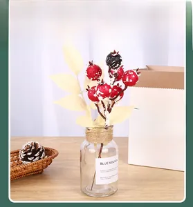 Branches de baies rouges et noires enneigées dans un vase pour décor d'hiver
