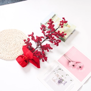 Artificial red holly berries branch with festive red bow for New Year home decoration