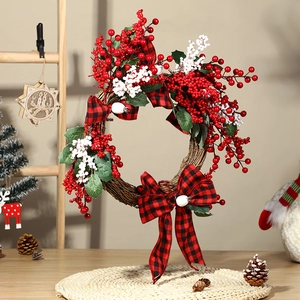 Artificial Christmas wreath with red berries, plaid bows and pine leaves on rattan base