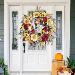 Close-up of autumn festive wreath with sunflowers, maple leaves, and a rustic bow detail