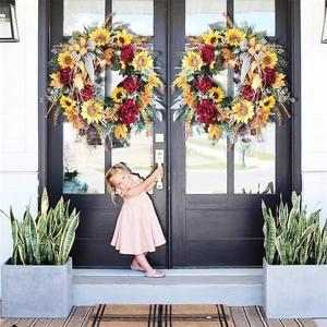 Close-up of autumn wreaths with sunflowers and striped bows on black double doors