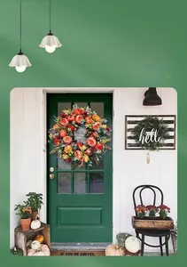 Detail of harvest wreath with pumpkins and roses on a dark green front door