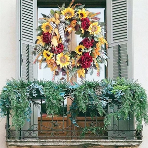 Detail of autumn wreath with sunflowers, maple leaves, and a striped bow on a grey shutter
