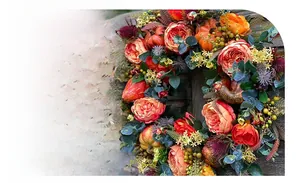 Detail of autumn wreath with orange roses, faux pumpkins, and eucalyptus leaves