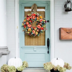 Outdoor view of autumn wreath with orange roses and pumpkins on a blue wooden door