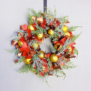 Detail of Christmas wreath with gold baubles, red ribbons and Merry Christmas text