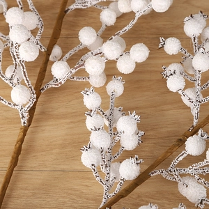 Frosted white artificial Christmas berry stems on a natural light brown wood background