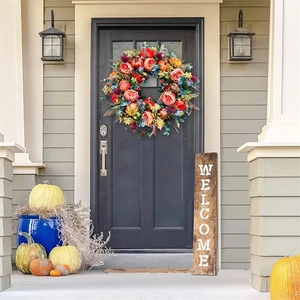 Detail of autumn harvest wreath with orange roses and berries on a black front door