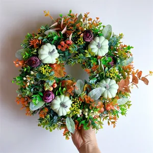 Detail of autumn harvest wreath featuring green pumpkins, purple roses and colorful berries