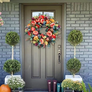Autumn harvest wreath with pumpkins and peonies hanging on a brown wooden door