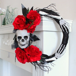 Detail of Halloween wreath with skull, red roses, and skeleton hands on white fireplace
