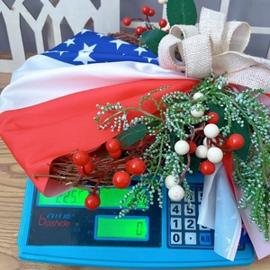 Detail shot of Patriotic USA flag wreath with burlap bow weighing 225g on a scale