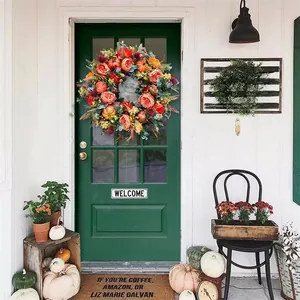 Macro shot of an autumn wreath featuring roses and pumpkins on a dark green door