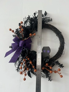 Close-up of a 45cm Halloween black owl wreath with purple LED eyes and orange glitter berries