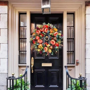 Detailed close-up of autumn harvest wreath with orange roses and mini pumpkins on door