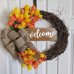 Detail of tulip wreath with natural grapevine base and rustic burlap bow on white door