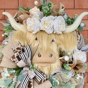 Easter Highland Cow wreath with white flowers and burlap bow on a red brick wall