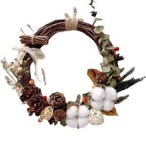 Rustic Christmas wreath with pine cones cotton and red berries on a natural rattan base