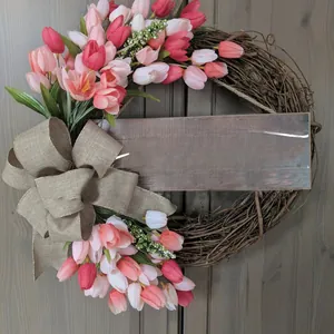 Detail of tulip and lavender wreath with burlap bow and a rustic wooden welcome sign