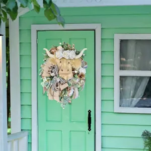 Detail of Highland Cow Easter wreath with spring floral accents on a pale green door