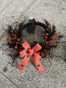 Close-up of Halloween wreath with black glitter cat and orange berry accents