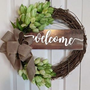 Detail of a welcome door wreath with artificial tulips, green leaves and burlap bow