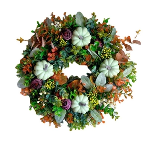 Autumn wreath with colorful eucalyptus, pumpkins, and harvest maple leaves on white background