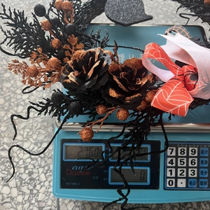 Detail of Halloween wreath with black and orange berries, showing weight of 216g on scale