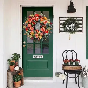 Autumn pumpkin wreath with yellow peonies and red berries on a dark green door