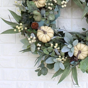 Autumn wreath featuring white pumpkins, eucalyptus leaves, pine cones, and berries