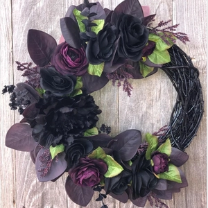 Close-up of gothic Halloween wreath featuring black and purple roses on a dark rattan base