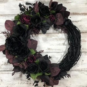 Gothic Halloween wreath with black and purple roses for front door decor on white wood background