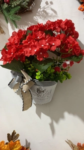 Dettaglio di gerani rossi artificiali in secchiello di metallo vintage con fiocco rustico