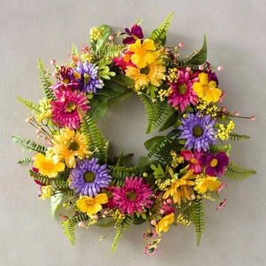 Dettaglio di ghirlanda floreale con margherite rosa, gialle e viola e foglie di felce