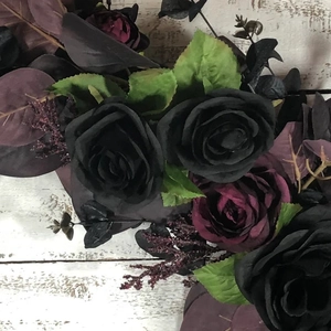 Gothic Halloween wreath with black roses and dark purple peonies on white wood wall