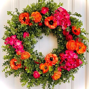 Ghirlanda di fiori primaverile con foglie di bosso, ranuncoli arancio e ortensie rosa