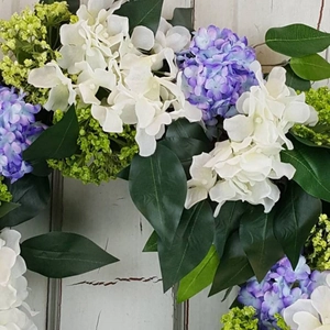 Macro detail of artificial hydrangea wreath with white and purple silk flowers and leaves