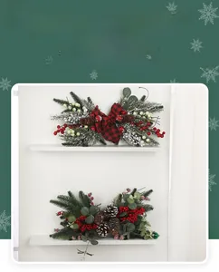 Detailed view of Christmas swags with pine needles, red berries, and festive bows on white shelf