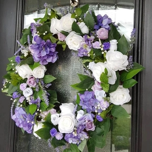 Detailed close-up of artificial hydrangea and rose wreath on a black door frame