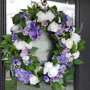 Round artificial wreath with purple hydrangeas and white roses on a black door