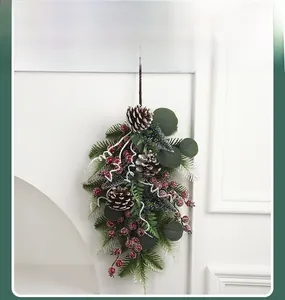 Detail of Christmas teardrop swag with frosted pine cones and red berries on white wall