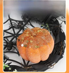 Close-up of orange glitter pumpkin with sequins and spooky Halloween spider web decor