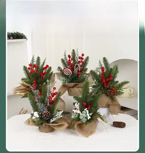 Close-up of mini Christmas trees with red berries, pine cones and rustic burlap base