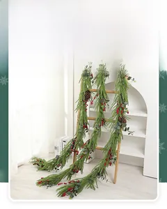 Drei künstliche Weihnachtsgirlanden mit roten Beeren und Zapfen an einer Holzleiter hängend