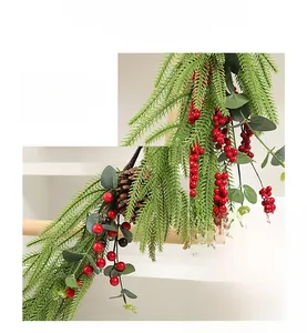 Detail einer künstlichen Tannengirlande mit roten Beeren und Zapfen für Weihnachten